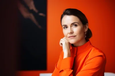 Professional Woman Posing Against Vibrant Orange Wall