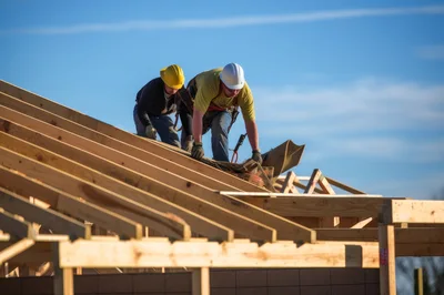 Construction Workers Installing Roof Sheathing on New House