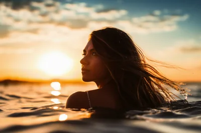 Young Woman Swimming In Ocean At Sunset
