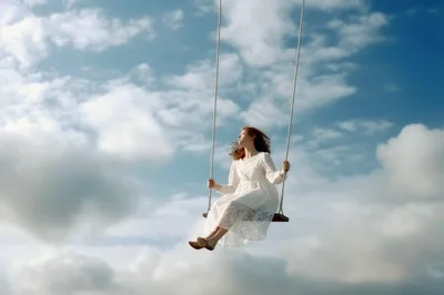 Young Woman In White Dress Swinging Against Cloudy Sky