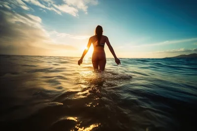 Woman Walking Into Ocean At Sunset