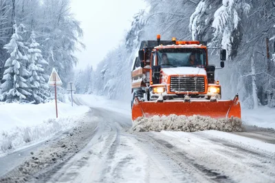 Orange Snowplow Clearing Snowy Road In Winter Forest