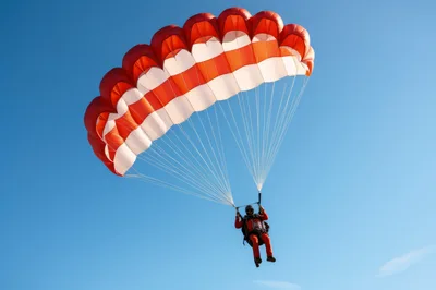 Skydiver Descending With Red And White Parachute