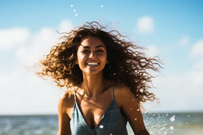 Happy Woman With Curly Hair Running On Beach