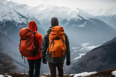 Two Hikers Standing On A Snowy Mountain Peak