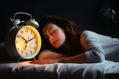 Young Woman Sleeping Beside A Glowing Alarm Clock