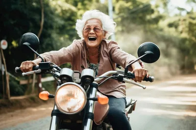 Joyful Elderly Woman Riding A Motorcycle Outdoors