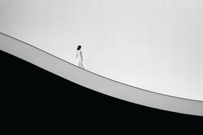 Woman In White Dress Walking On Minimalist Architectural Ramp
