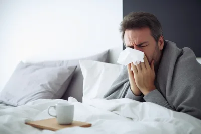 Sick Man Blowing Nose In Bed