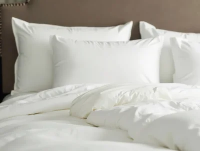White Bedding With Fluffy Pillows On A Bed