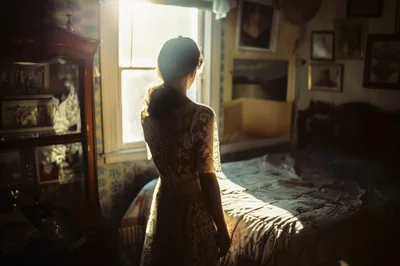 Woman In Lace Dress Standing By Bedroom Window