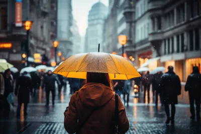 Person Walking Through Rainy City Street With Yellow Umbrella