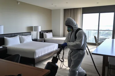 Professional Cleaner Sanitizing Hotel Room in Hazmat Suit