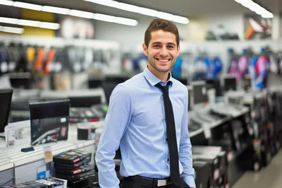 Smiling Male Retail Employee Standing In Electronics Store