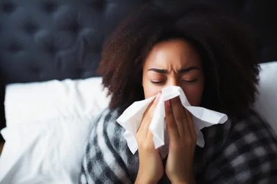 Young Woman Blowing Her Nose In Bed