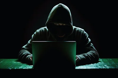 Hacker Wearing A Hoodie Working On A Laptop