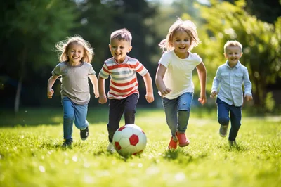 Four Happy Children Playing Soccer in a Sunny Park