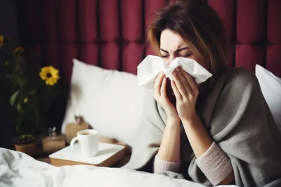 Sick Woman Blowing Her Nose In Bed