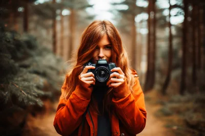 Young Woman Holding Camera In Autumn Forest