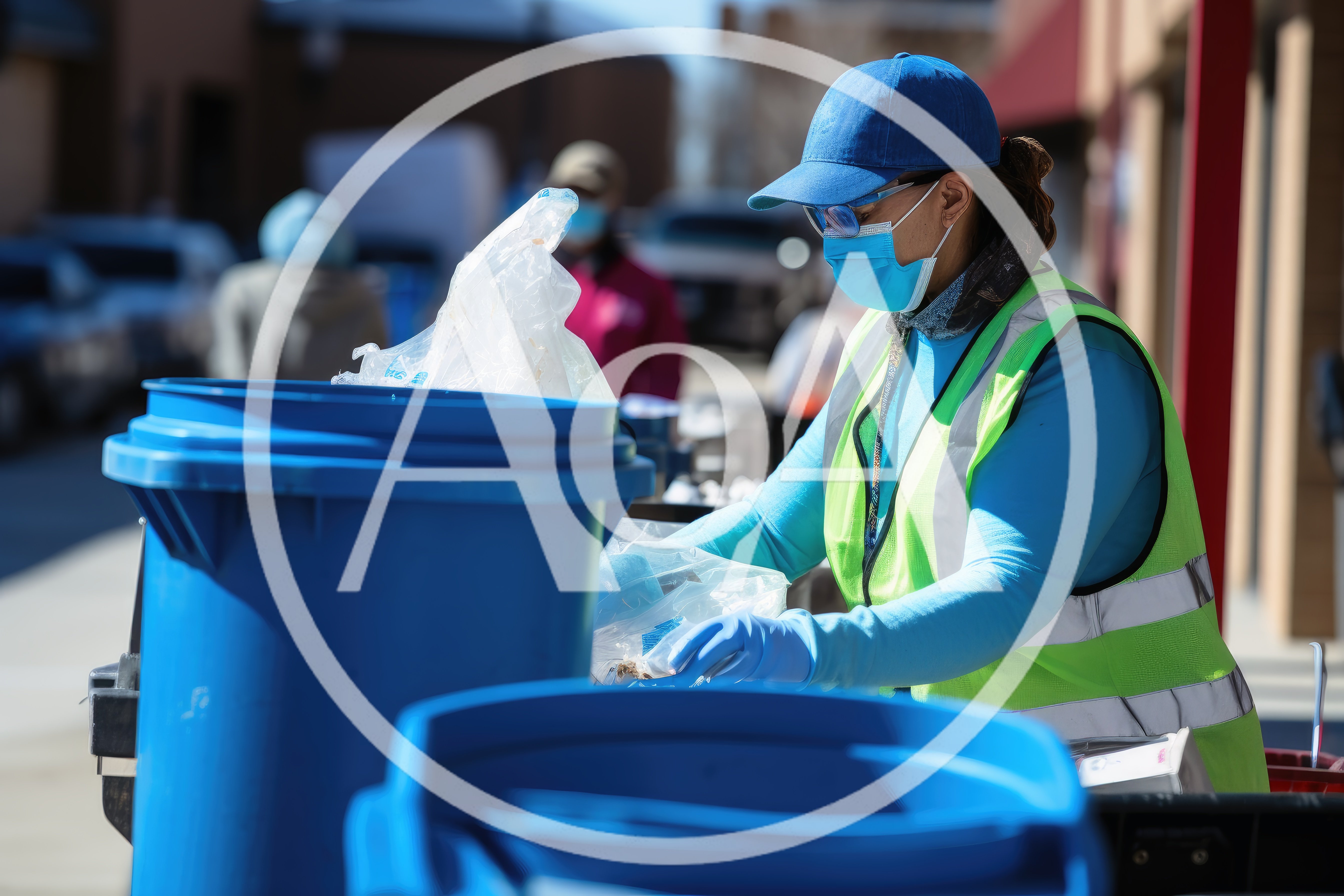 Volunteer Sorting Food Donations Into Blue Bins