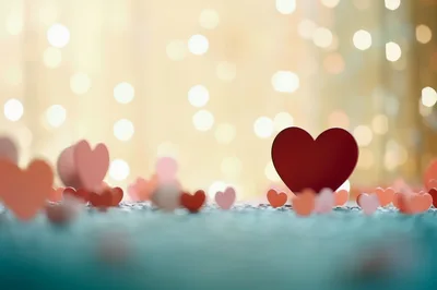 Red Heart Decorations on Teal Surface with Bokeh Background