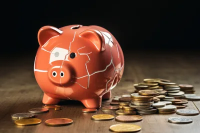 Cracked Orange Piggy Bank With Scattered Coins