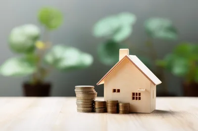 Wooden House Model With Stacks Of Coins