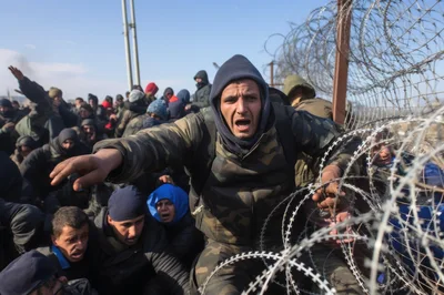 Migrants Pushing Against Barbed Wire Border Fence