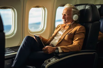 Mature Businessman Relaxing With Tablet On Airplane