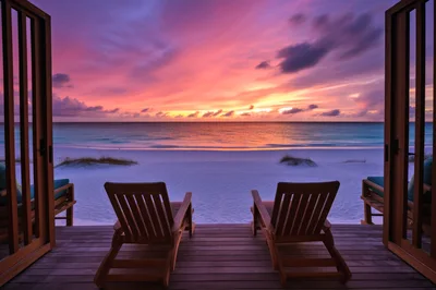Two Wooden Lounge Chairs Overlooking A Tropical Beach Sunset