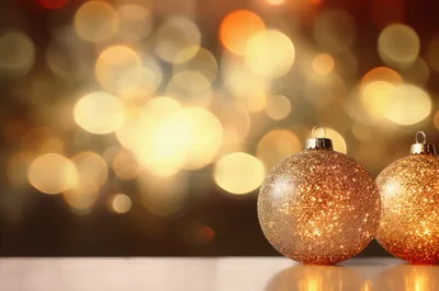 Two Golden Glittering Christmas Ornaments On Reflective Surface
