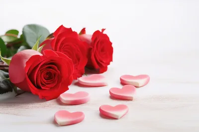 Red Roses and Heart Shaped Candies on White Wood