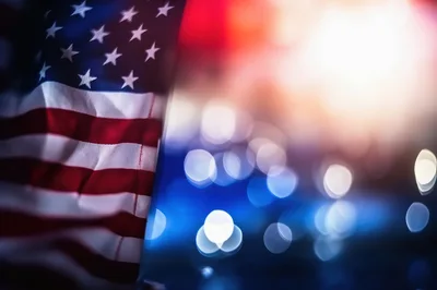 American Flag Waving Against Blurred City Lights