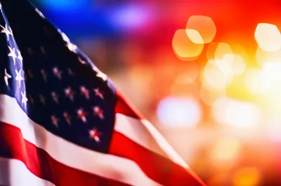American Flag Waving Against Blurred Emergency Lights