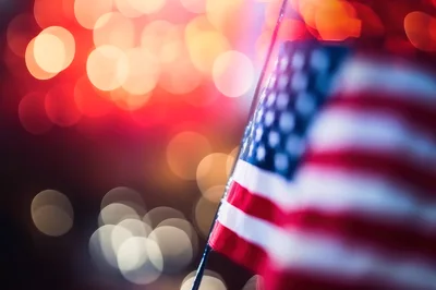 American Flag Waving Against Blurred Festive Bokeh Lights