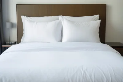 Modern Hotel Bed With White Linens And Pillows