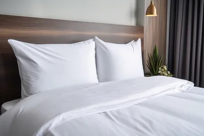 Modern Hotel Bedroom With White Bedding And Wooden Headboard