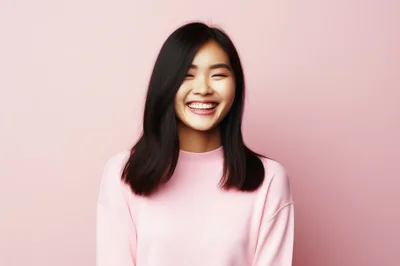 Young Asian Woman Laughing Against Pink Background