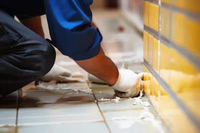 Professional Tiler Applying Grout To Floor Tiles
