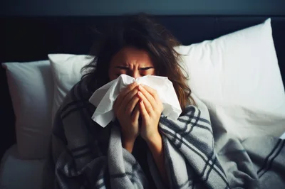 Sick Woman Blowing Her Nose In Bed