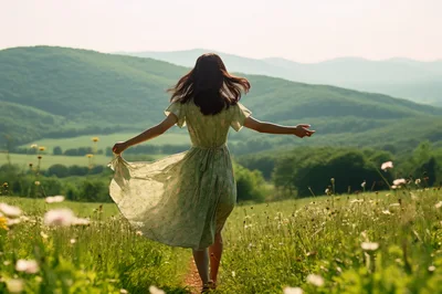 Young Woman Walking Through A Sunny Wildflower Meadow