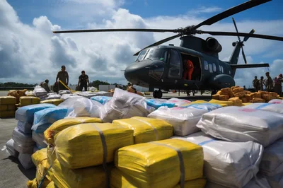 Military Personnel Loading Supplies Near Helicopter