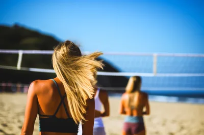 Three Women Playing Beach Volleyball On A Sunny Day
