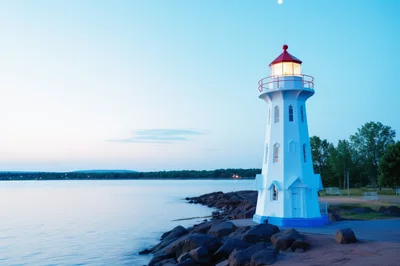 Illuminated Lighthouse On A Rocky Shore At Twilight
