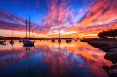 Sailboats Anchored In A Calm Harbor At Sunset
