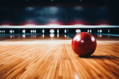 Red Bowling Ball Resting On Wooden Lane