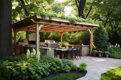 Outdoor Kitchen And Dining Area Under Wooden Pergola