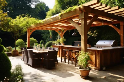 Outdoor Kitchen And Dining Area Under Wooden Pergola
