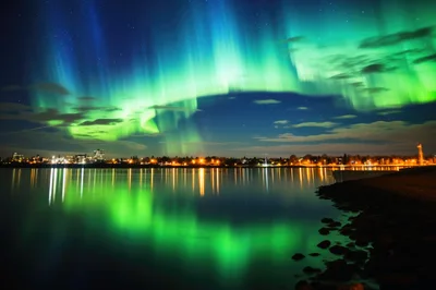 Vibrant Aurora Borealis Over A Calm City Waterfront