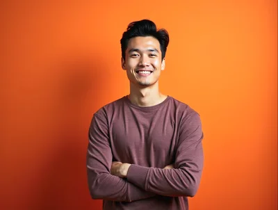 Smiling Asian Man With Crossed Arms Against Orange Background